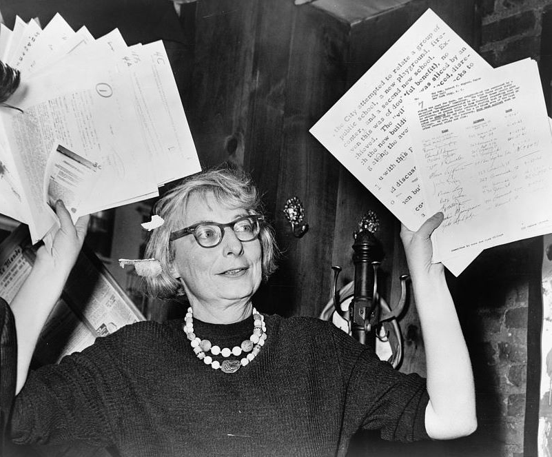 1961 photo of Mrs. Jane Jacobs, chairman of the Committee to save the West Village, holds up documentary evidence at a press conference at Lions Head Restaurant at Hudson & Charles Sts. From the New York World-Telegram and the Sun Newspaper Photograph Collection, in the Library of Congress.